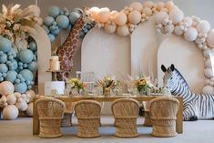 a giraffe and zebra are sitting in front of a table with balloons on it