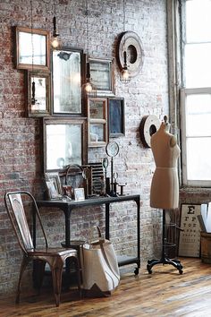 a brick wall with several frames on it and a chair next to it in front of the window