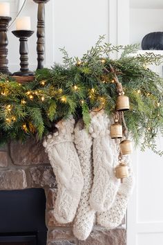 christmas stockings hanging from a mantel with lights and garland on it's mantle