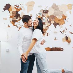 a man and woman hugging each other in front of a world map on the wall