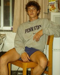 a young man sitting on top of a wooden chair