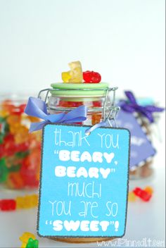 a jar filled with gummy bears sitting on top of a table next to a sign