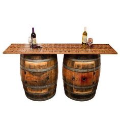 two wine barrels sitting on top of each other next to a table topped with bottles and glasses