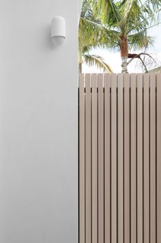 a white wall mounted light on the side of a building next to a palm tree