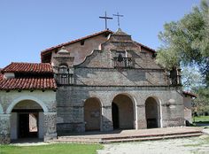 an old church with red tile roof and stone steps leading up to the front door