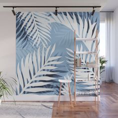 a blue and white palm leaf wall mural in a living room with wooden floors, a ladder