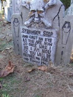 a grave with writing on it and a creepy face carved into the stone next to it