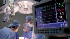 two doctors in scrubs are operating on an electronic monitor with medical equipment around them