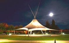 a large white tent sitting on top of a lush green field under a full moon