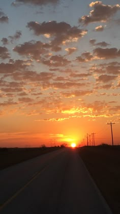 the sun is setting over an empty road