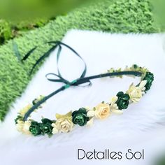 a green and white flower headband laying on top of a grass covered ground with the words details so written below it