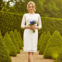 a woman wearing a white dress and holding a bouquet of blue flowers in her hand