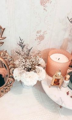 there is a mirror, candle and flowers on the table in front of the wall