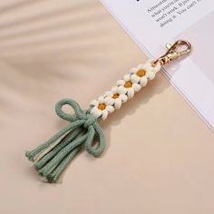 a keychain with flowers on it and a ribbon attached to the end, sitting on top of a piece of paper