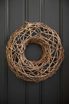 a close up of a wreath on a door with black paint and wood trimming