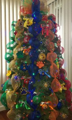 a brightly colored christmas tree decorated with ribbons and bows in the shape of dogs on it