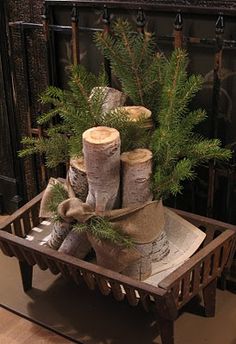 a wooden crate filled with logs and christmas tree branches sitting on top of a hard wood floor