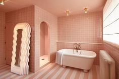 a bath room with a tub and a sink inside of it on a striped floor