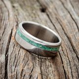 a wedding ring sitting on top of a piece of wood with green writing on it