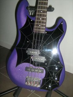 a purple and black guitar sitting on top of a stand