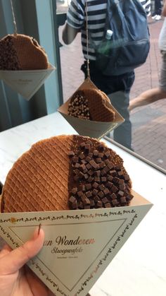 a waffle with chocolate toppings hanging from it's sides in front of a window