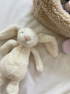 a white stuffed rabbit laying on top of a bed next to a bottle of milk