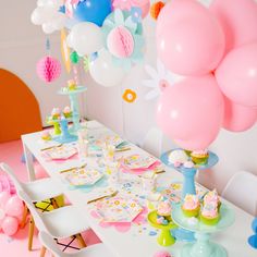 a table set up with balloons, cake and cupcakes