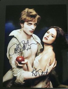 the twilight saga signed autographed by actors robert taylor and elizabeth janen, who appear to be holding an apple