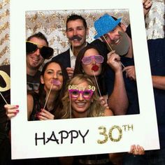 a group of people posing for a photo in front of a sign that says happy 30th