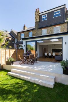 an outdoor patio with steps leading up to the back door and dining table in the foreground