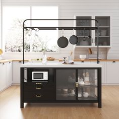 a kitchen with white walls and wooden flooring, an island in the middle has pots on it