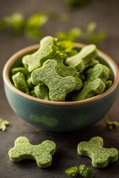 a bowl filled with green dog treats on top of a table