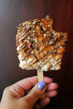 a hand holding an ice cream bar covered in caramel and nuts