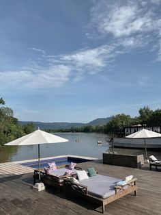 two lounge chairs sitting on top of a wooden deck next to a body of water