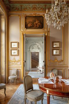 an elegant dining room with chandelier and paintings on the walls