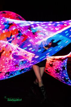 a woman is walking in front of a large colorful object with lights all over her body