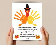 someone holding up a thanksgiving card with a turkey in the middle and hand prints on it