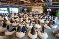 a large group of people sitting on bean bags in an open room with lots of windows