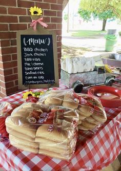 a table topped with lots of food next to a chalkboard sign and red checkered table cloth