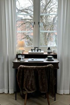 a table with a mirror and two lamps in front of a window