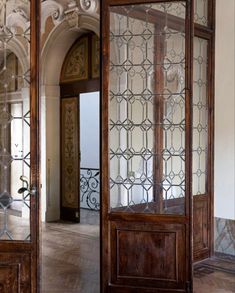 an ornate wooden door with glass panels on the front and back doors are open to let in light