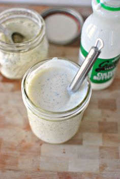 two jars filled with white liquid sitting on top of a wooden table