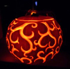 a carved pumpkin sitting on top of a table in the dark with flames coming out of it