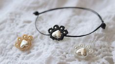 three dog paw bracelets on a white sheet with black and gold bead accents