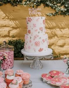 a white cake sitting on top of a table next to cupcakes