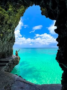 a man standing on the edge of a cave looking out at the ocean from inside