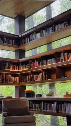 a living room filled with lots of books and furniture next to a large glass window