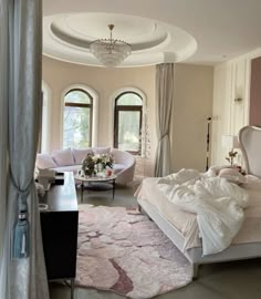 a large bedroom with white furniture and chandelier hanging from the ceiling, along with round windows