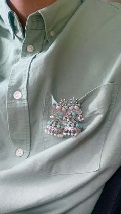 a close up of a person wearing a green shirt with buttons on the collar and chest