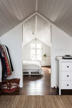 an attic bedroom with white walls and wood floors